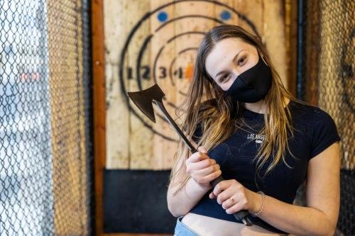 Teenage girl holding axe at an axe throwing range with target be